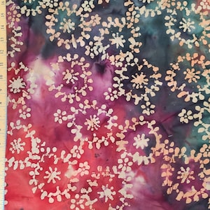 Może przedstawiać: Zbliżenie na tkaninę z wzorem batikowym. Tkanina jest połączeniem kolorów czerwonego, fioletowego i turkusowego z białym wzorem małych kółek i kropek.