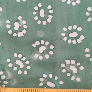 May include: Green fabric with a white batik pattern of repeating circles. The fabric is measured with a ruler that says "Factory Furnit"