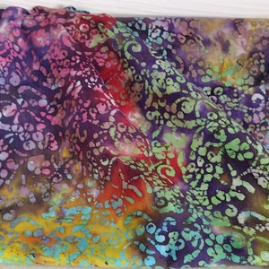 以下が含まれることがあります： 紫、赤、緑、黄、茶色の色合いでバティック模様が施されたカラフルな生地。生地には渦巻き状の花柄のデザインが施されています。