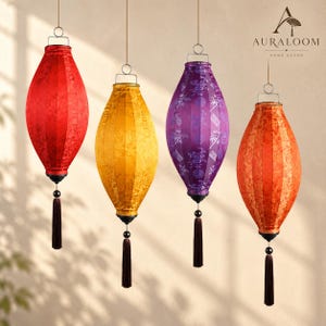 May include: Four hanging lanterns in red, yellow, purple, and orange, each featuring a patterned fabric surface, a silver metal top loop, and a dark brown tassel at the bottom. The AURALOOM HOME DECOR logo is visible in the top right corner.