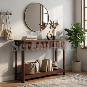May include: A dark wood console table with three slatted drawers and a lower shelf. The table holds books, a geometric wire sculpture, and two ceramic vases. A round gold-framed mirror hangs above, with a woven basket and books on the shelf.