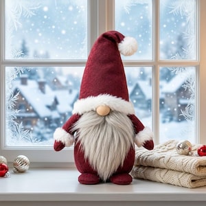 May include: A plush gnome figurine featuring a tall, pointed dark red felt hat with a white faux fur trim and pom-pom. The gnome has a round wooden nose, a long gray faux fur beard, and dark red sleeves with white faux fur cuffs.