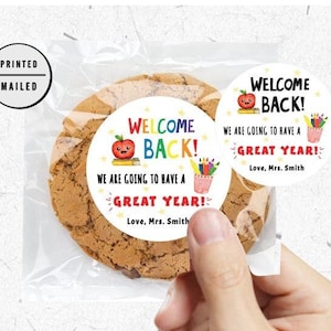 Puede incluir: Dos pegatinas redondas y coloridas de bienvenida de regreso a la escuela con una manzana roja, l&aacute;pices y un porta l&aacute;pices. El texto en las pegatinas dice "&iexcl;Bienvenidos de vuelta! Vamos a tener un gran a&ntilde;o! Con cari&ntilde;o, Sra. Smith".