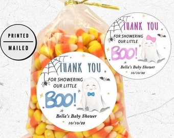 Puede incluir: Dos pegatinas redondas de agradecimiento con un fantasma y el texto "¡Gracias por celebrar a nuestro pequeño Boo!" y "Baby Shower de Bella 10/10/22". Las pegatinas están en una bolsa de plástico transparente llena de maíz dulce.