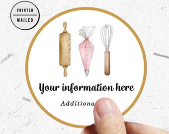Puede incluir: Una pegatina redonda con un borde dorado que presenta un rodillo, una manga pastelera y un batidor. El texto "Your information here" está impreso en negro debajo de las herramientas de horneado.