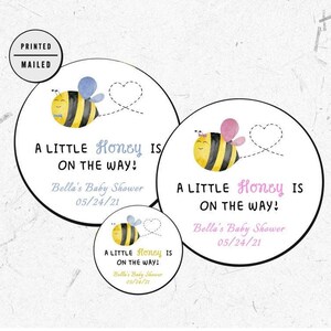May include: Three round baby shower favor stickers with a cartoon bee illustration and the text "A little Honey is on the way!"  Bella's Baby Shower 05/24/21