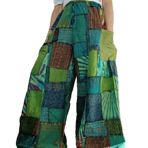 Op de afbeelding: Broek met wijde pijpen en een patchwork-ontwerp in diverse tinten groen en blauw. Het kledingstuk is voorzien van een tailleband met trekkoord, zijzakken en een mix van vierkante stoffen met patronen en zichtbare stiksels over het geheel.