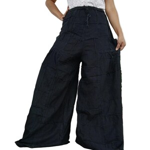 May include: Black wide-leg trousers featuring a patchwork construction with visible horizontal and vertical seams throughout the fabric. The trousers have an elasticated waistband with a drawstring closure and a loose, flowing silhouette.