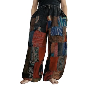 May include: Wide-leg pants featuring a patchwork design with various fabric squares in shades of black, brown, blue, and rust orange. The pants have an elasticized drawstring waistband and a loose, flowing fit with visible printed patterns.