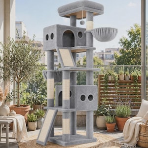 May include: A tall, multi-level cat tree covered in soft gray fabric, featuring two enclosed cubbies with circular cutouts, multiple sisal-wrapped scratching posts, a hanging fabric hammock, a top platform, and two inclined ramps with sisal surfaces.
