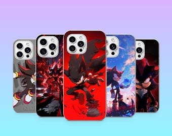 Peut inclure: Cinq coques de smartphone représentant le personnage Shadow the Hedgehog dans diverses poses d'action et décors. Les designs incluent un fond gris, une scène rouge enflammée, un fond rouge vif, un paysage de ciel bleu et un portrait rouge sombre.