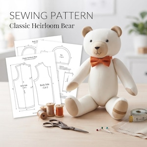 May include: A sewing pattern for a Classic Heirloom Bear with printed instructions, a stuffed bear toy with a tan muzzle and orange bow tie, three wooden spools of thread, metal scissors, sewing pins, and a measuring tape showing 2 inches.
