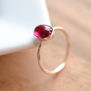 May include: A silver ring with a red oval gemstone.
