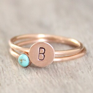 May include: Two gold rings with a turquoise stone and a letter 'B' engraved on the larger ring.