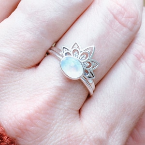 Peut inclure: Une bague en argent avec un motif floral délicat et un centre en pierre de lune blanche.