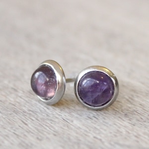 May include: A pair of silver stud earrings with round amethyst gemstones.