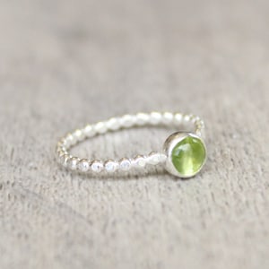 May include: A silver ring with a beaded band and a green gemstone.