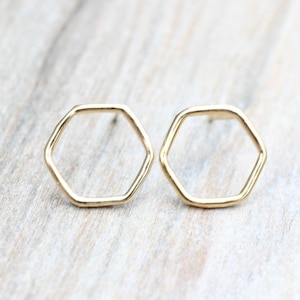 May include: A pair of gold hexagon shaped stud earrings.