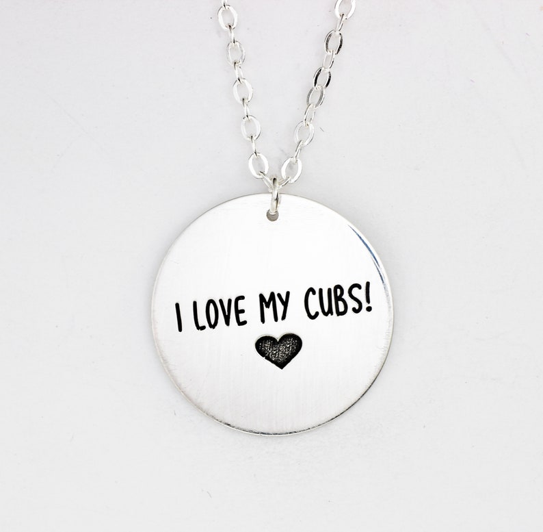 May include: Silver necklace with a round pendant that says "I love my Cubs!" with a small heart below the text.