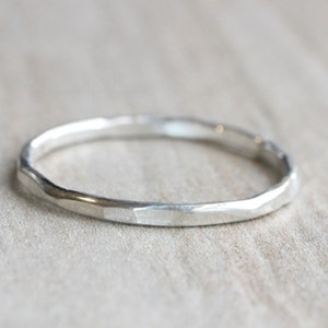 May include: A simple silver band ring with a hammered texture.