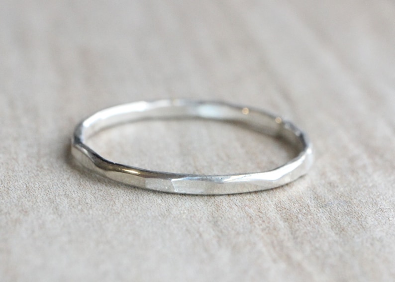 May include: A simple silver band ring with a hammered texture.
