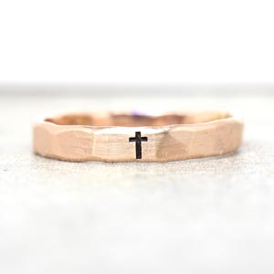 Può includere: Un anello a fascia martellato in oro rosa con una piccola croce incisa sulla parte superiore.