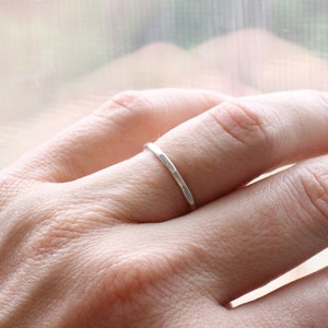 May include: A simple silver band ring worn on a finger.