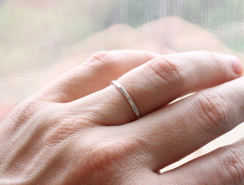 May include: A simple silver band ring worn on a finger.