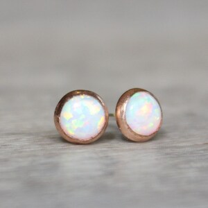 May include: A pair of rose gold stud earrings with white opal gemstones.