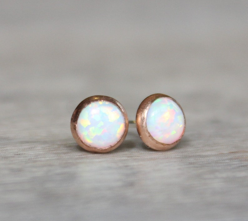 May include: A pair of rose gold stud earrings with white opal gemstones.