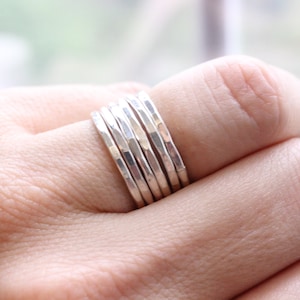 May include: A set of six silver hammered stacking rings. The rings are worn on a finger and are stacked on top of each other.