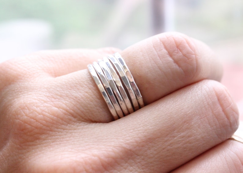 May include: A set of six silver hammered stacking rings. The rings are worn on a finger and are stacked on top of each other.