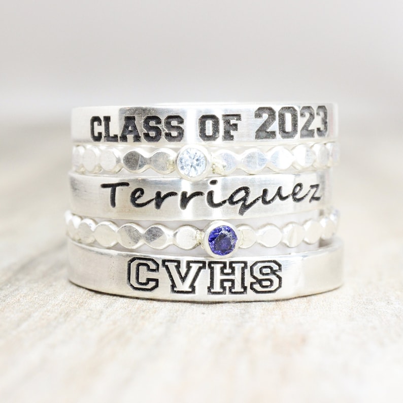 May include: Silver graduation ring set with three bands. The top band reads "Class of 2023", the middle band reads "Terriquez", and the bottom band reads "CVHS".