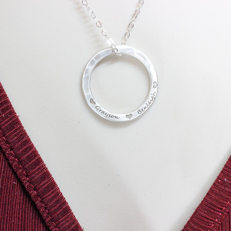 May include: Silver necklace with a hammered circle pendant engraved with the names "Grayson" and "Benleigh" and small hearts.
