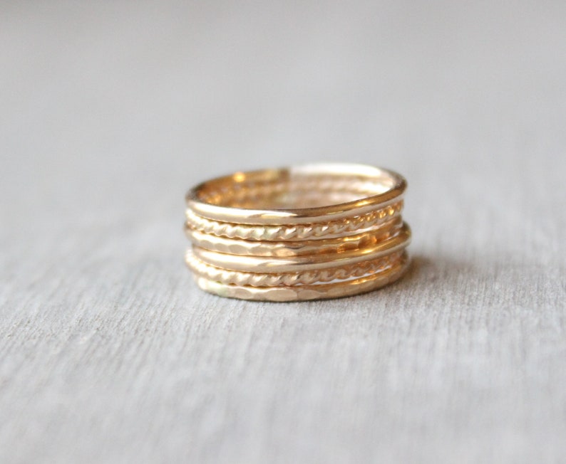 May include: A set of six gold stacking rings with different textures, including hammered, twisted, and smooth.