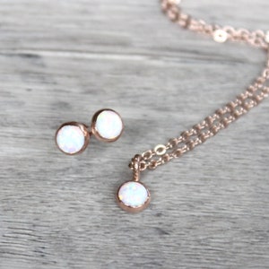 May include: A set of rose gold jewelry featuring a necklace and earrings with white opal stones.