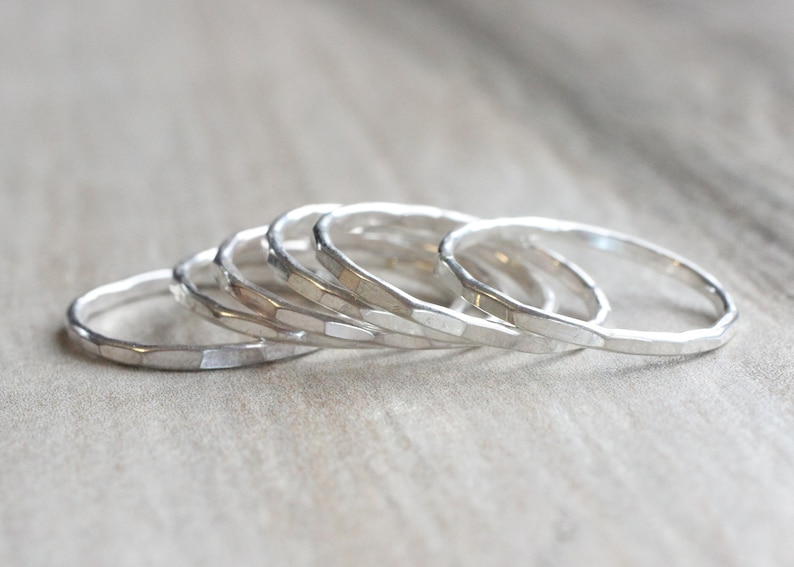 May include: A set of five silver hammered stacking rings. The rings are all different sizes and are stacked on top of each other.
