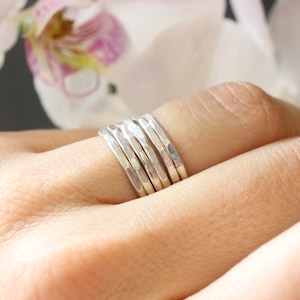 May include: A set of five silver hammered stacking rings. The rings are worn on a finger and are stacked on top of each other.