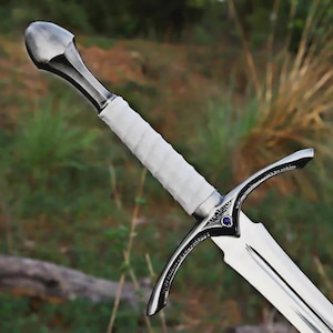 May include: A silver-toned sword featuring a white, spirally wrapped handle and a polished metal pommel. The crossguard is detailed with intricate engravings and a small, circular blue gemstone set at the center, leading to a sharp blade.
