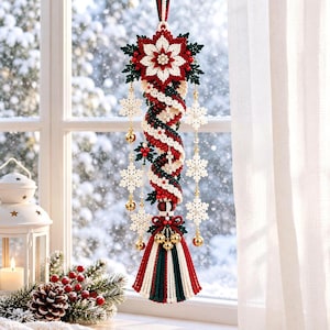 Peut inclure: Une décoration suspendue composée d'une spirale centrale de perles rouges, blanches et vertes, surmontée d'une grande fleur de poinsettia. Elle comprend des flocons de neige blancs, des clochettes dorées et un pompon multicolore.
