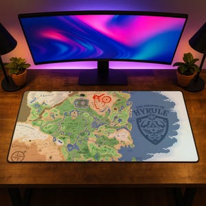 May include: A rectangular desk mat featuring a detailed map of the Kingdom of Hyrule. The design includes various geographical regions, terrain markers, and the text The Kingdom of Hyrule alongside a large crest emblem on the right side.