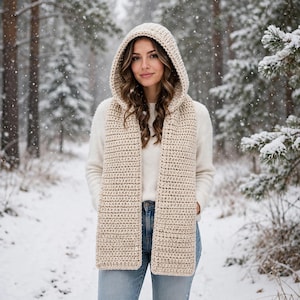 May include: A beige hooded scarf featuring a thick, textured crochet knit pattern. The accessory consists of a deep hood that transitions into two long, rectangular panels hanging down the front, crafted from a solid, neutral-colored yarn.