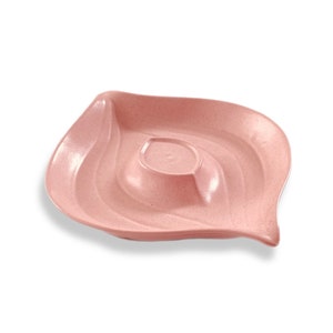 May include: A pink leaf-shaped serving dish with a small dip bowl in the center. The dish is made of a textured material and has a wavy design.