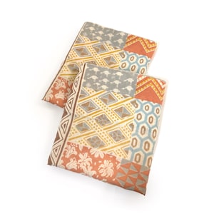 May include: Two rectangular fabric items with a patchwork design. The patterns include geometric shapes, floral motifs, and various colors such as orange, blue, gray, and yellow. The items are arranged on a white background.