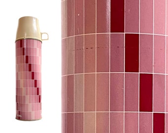 May include: A pink and red thermos with a white lid and handle. The thermos has a geometric pattern of squares.
