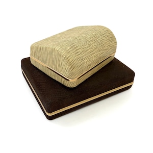 May include: Two rectangular boxes, one stacked on top of the other, against a white background. The top box is a light gold color with a textured, ridged pattern. The bottom box is dark brown with a similar ridged texture. Both have gold trim.