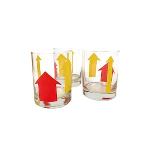 May include: Set of four clear glass tumblers with yellow and red arrow designs. The arrows point upwards.