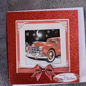 May include: A square greeting card with a red glitter border featuring a vintage orange car under a crescent moon and snowflakes. The card includes a decorative white frame, a dark red ribbon bow, and an oval label with the text Merry Christmas.