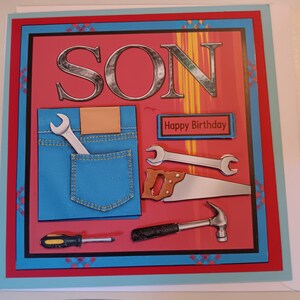 May include: A square greeting card with a red background featuring the word SON in large silver letters. It displays a blue denim pocket with a wrench, a hand saw, a hammer, a screwdriver, and a sign that reads Happy Birthday.