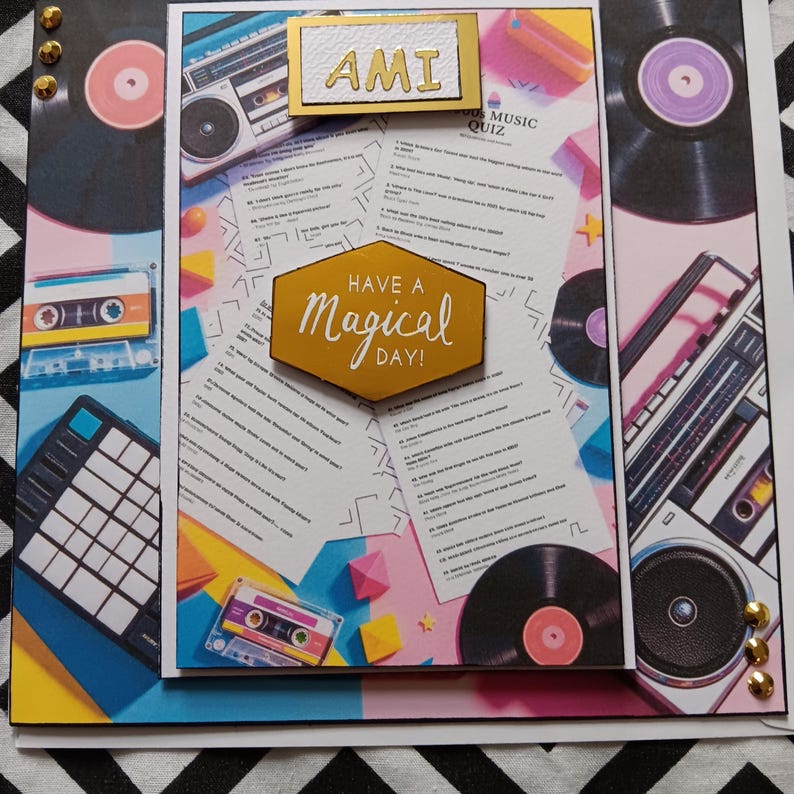 May include: A handmade greeting card featuring a music quiz theme with retro boomboxes, cassette tapes, and vinyl records. The center includes a gold hexagonal plaque with the text "HAVE A magical DAY!" and a white rectangular tag labeled "AMI".
